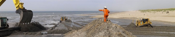 Bulldozers verdelen zand over een strand